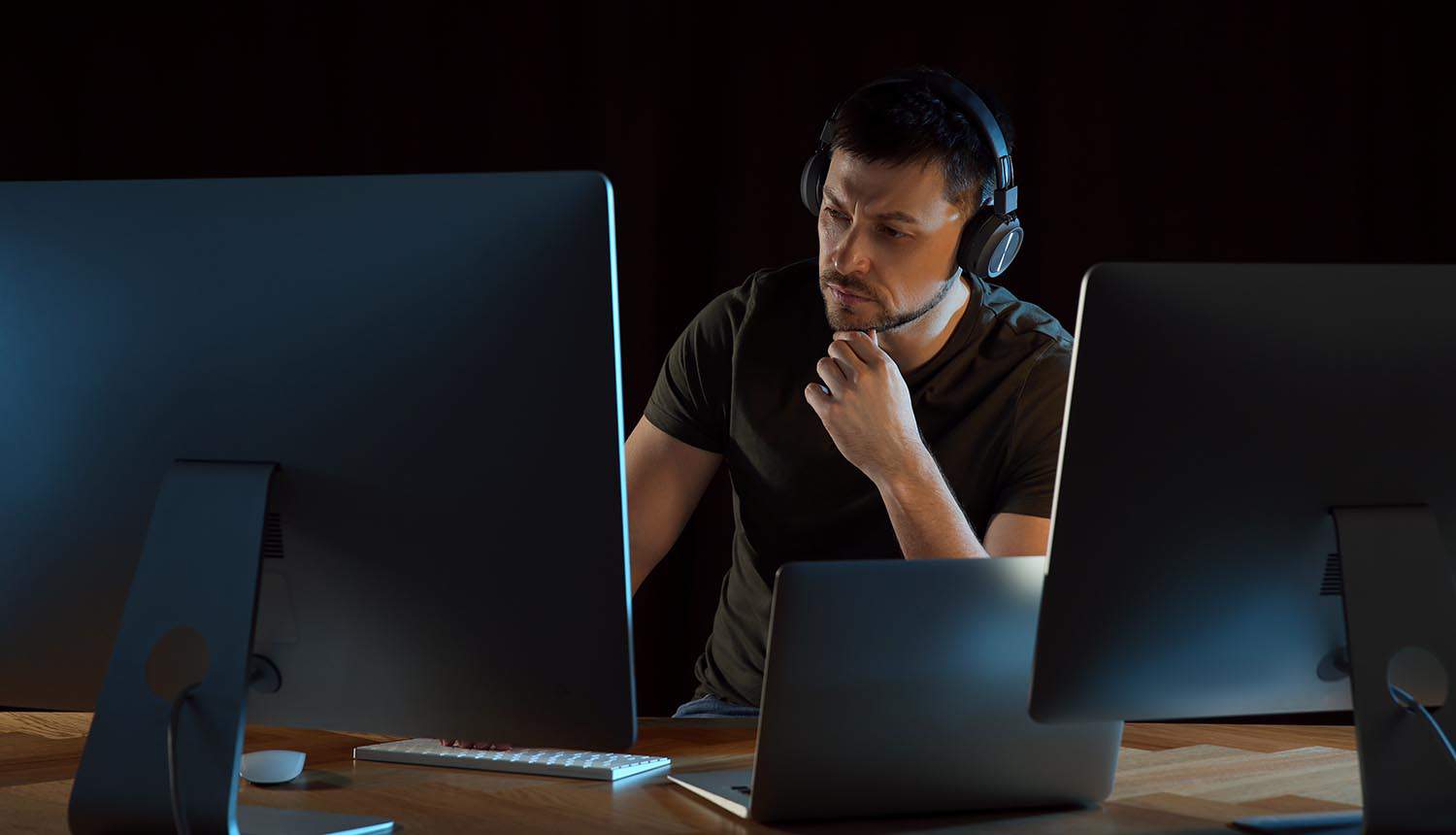 Ethical hacker with headphones working in office at night